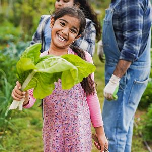 Girl smiling with chard in a garden