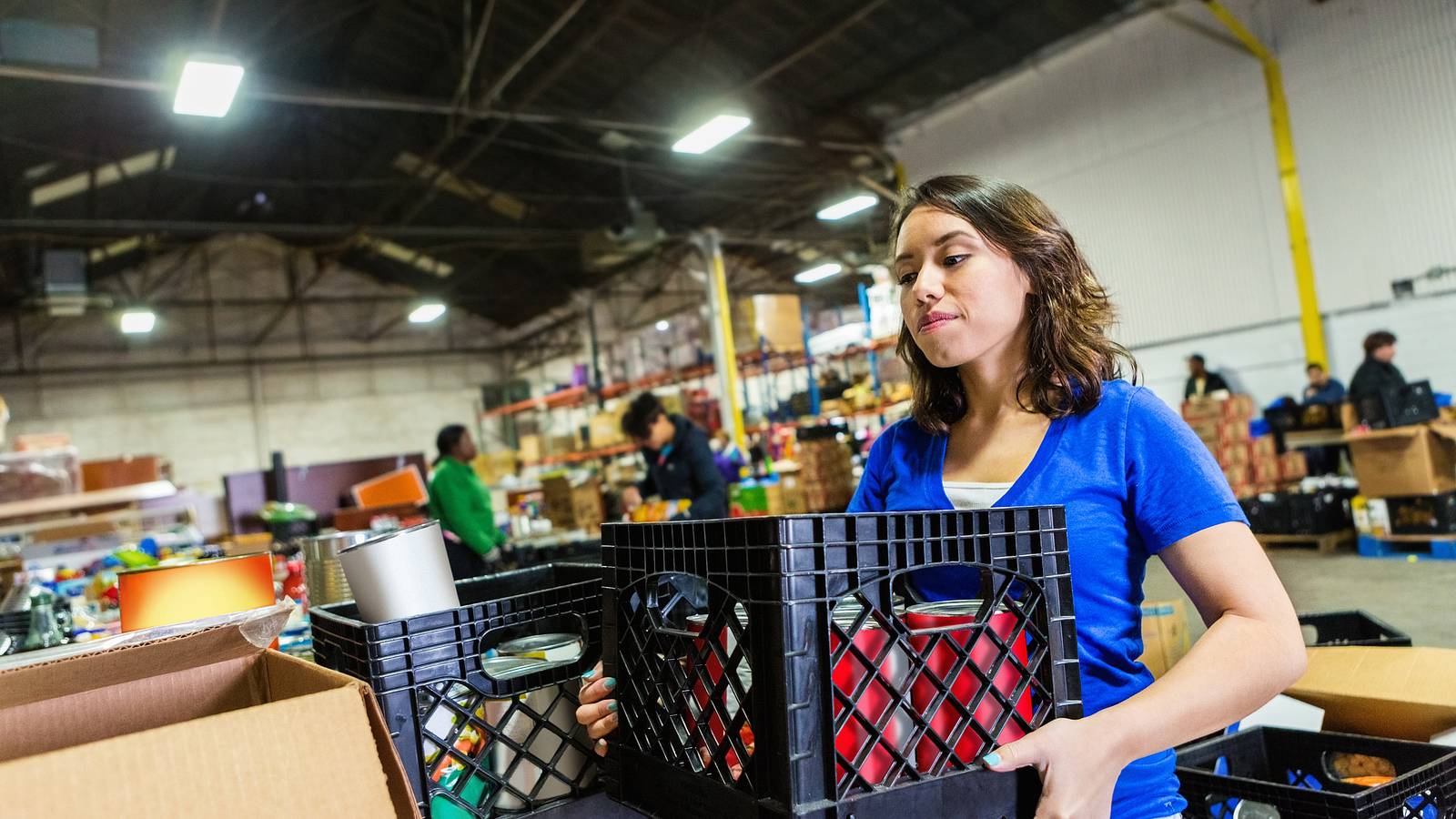 Image of a woman holding a box of food at a food bank.