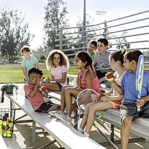Image of a group of elementary school students sitting on bleachers with tennis gear and equipment. Image from USTA's NET Generation initiative for PHA's 2017 #PHABack2School campaign.