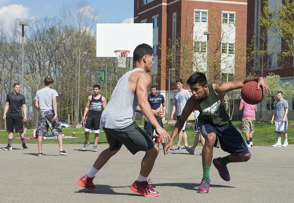 Image of students at Binghamton University playing basketball outdoors. Binghamton University participates in PHA's Healthier Campus Initiative. 