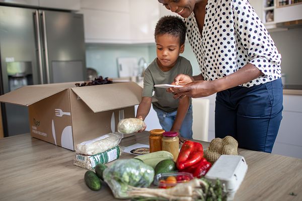 Mom and son with box of veggies and phone
