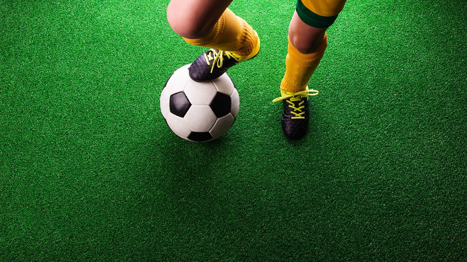 Image of young athlete with foot on soccer ball.