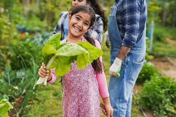 Girl smiling with chard in a garden