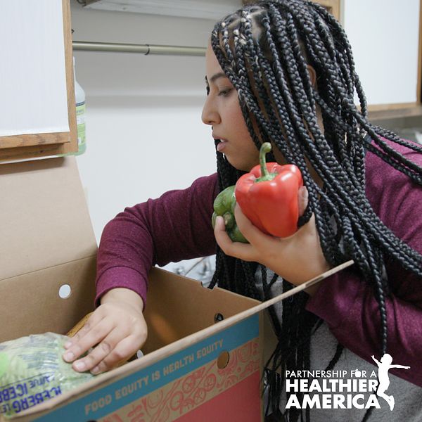 Perla from Lincoln, NE looking at the produce in a Good Food for All box