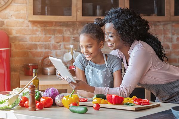 A mother and daughter follow along with the PHA cookbook in the kitchen