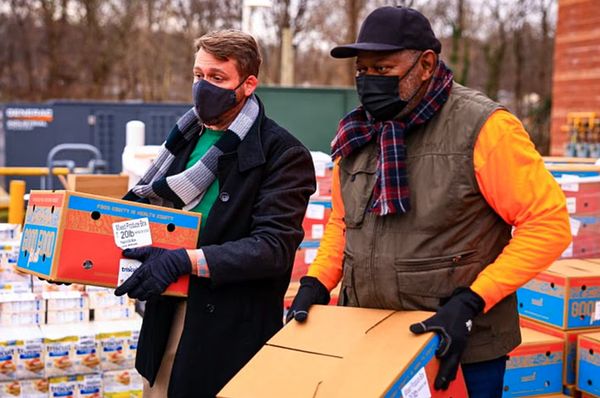 Two people pass out Good Food for All boxes