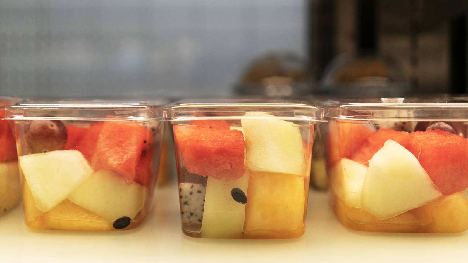 Image of fresh cut fruit in plastic packaging at a convenience store.