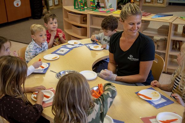 Chef Delanya sitting with students eating healthy snacks. 
