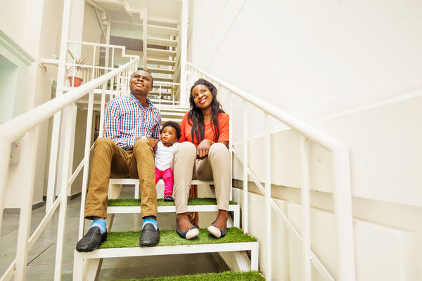Family sitting on stairs in apartment complex.