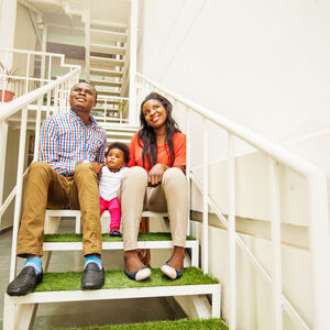 Family sitting on stairs in apartment complex.