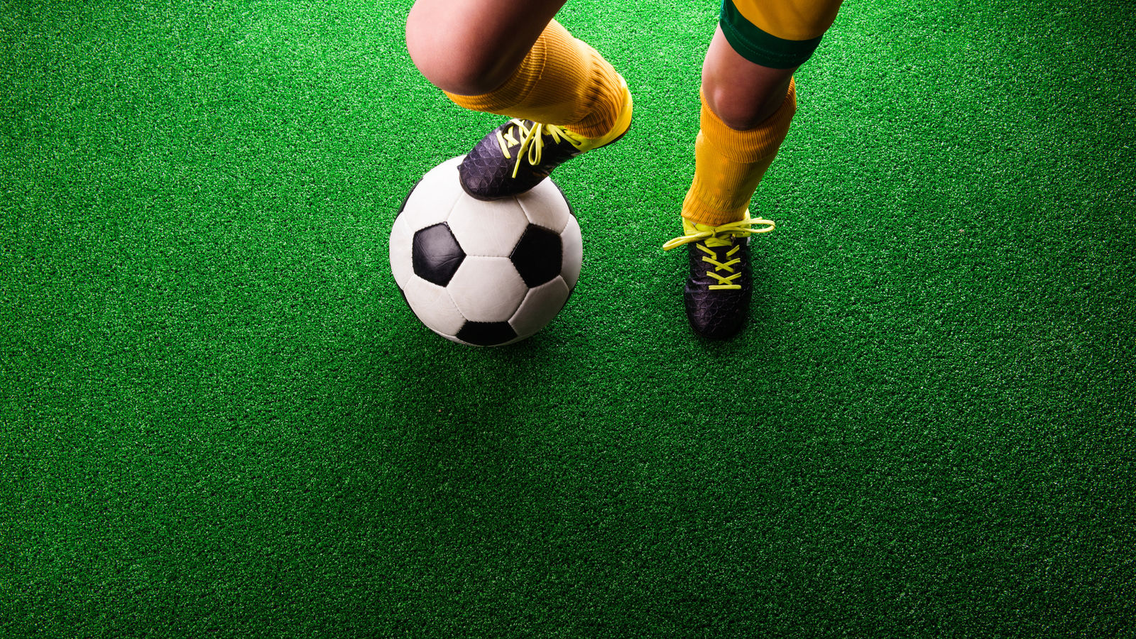 Image of young athlete with foot on soccer ball.