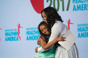 Image of a student hugging Michelle Obama after delivering Obama's introduction at Partnership for a Healthier America's 2017 Building a Healthier Future Summit.