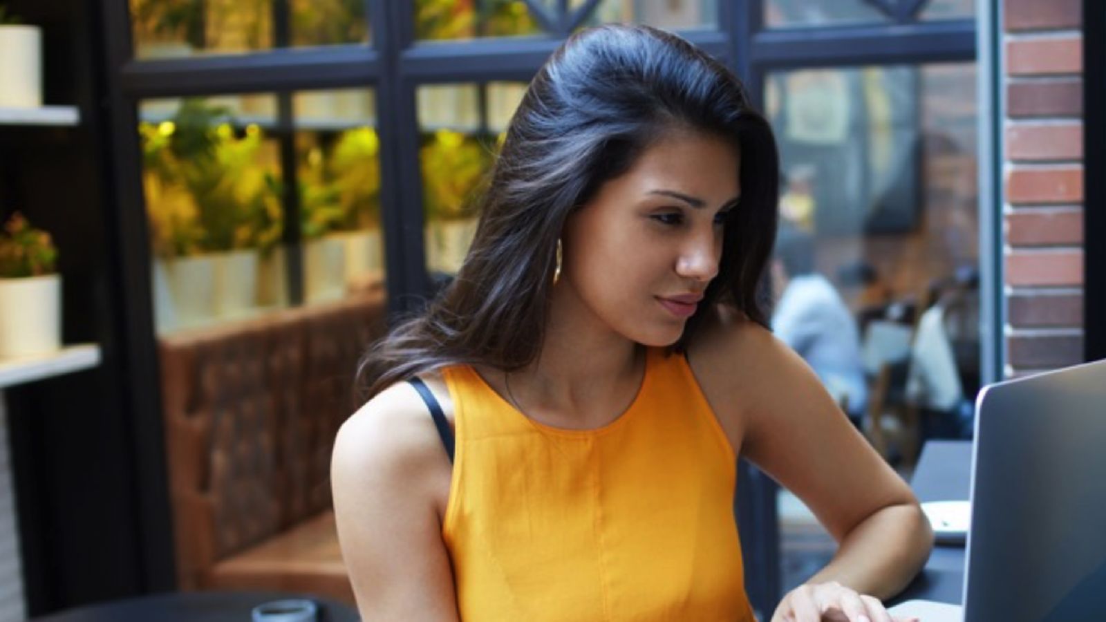 Image of a Latinx college student working on a laptop outdoors. 