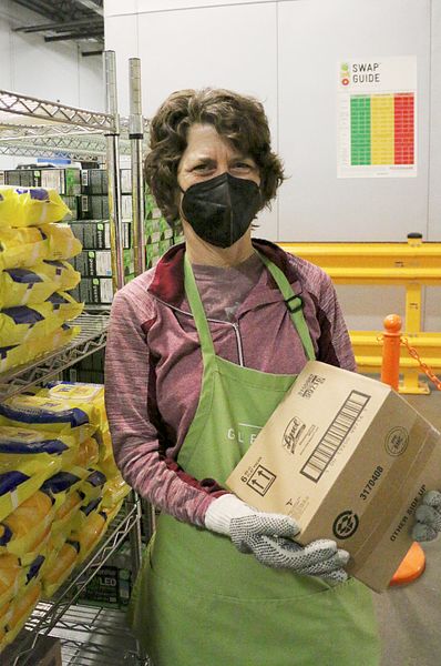A volunteer stocks items near a poster with the nutrition ranking guidelines at Gleaners’ on-site Cynthia H. Hubert Community Cupboard food pantry