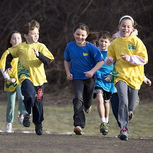 Image of children running across a field. These are participants in a children's physical activity program through BOKS.