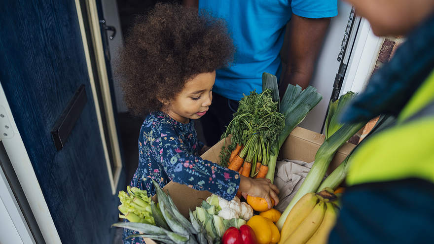 child reaching into a produce box