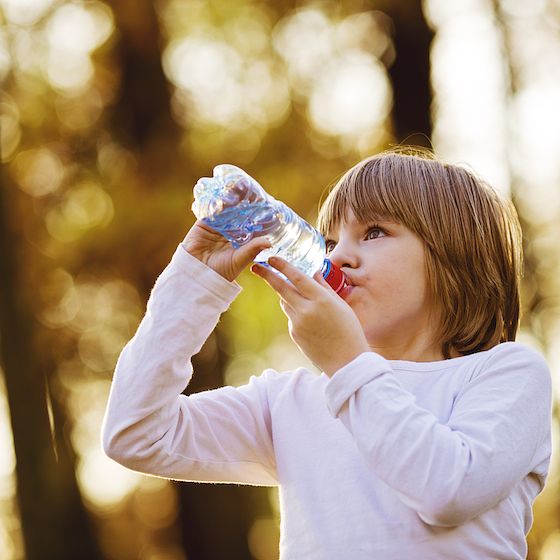 Image of young girl drinking water outdoors. 