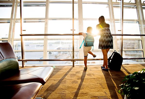 Image of woman and child staring out a window at an airport. 