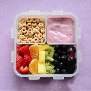 Image of whole grain cereal, yogurt and fruit in a children's lunchbox container. 