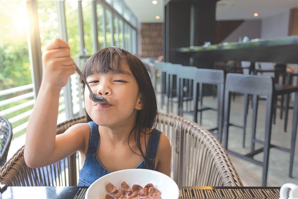 Image of a small child eating in a restaurant. 