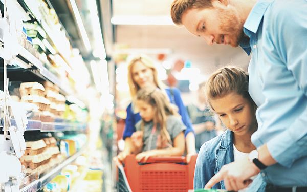 Image of a dad and daughter reading a food label in a grocery store. 
