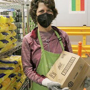 A volunteer stocks items near a poster with the nutrition ranking guidelines at Gleaners’ on-site Cynthia H. Hubert Community Cupboard food pantry