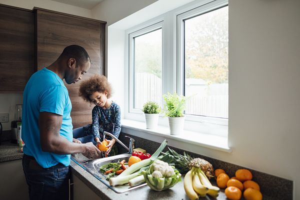 A father and daughter washing fruits and vegetables
