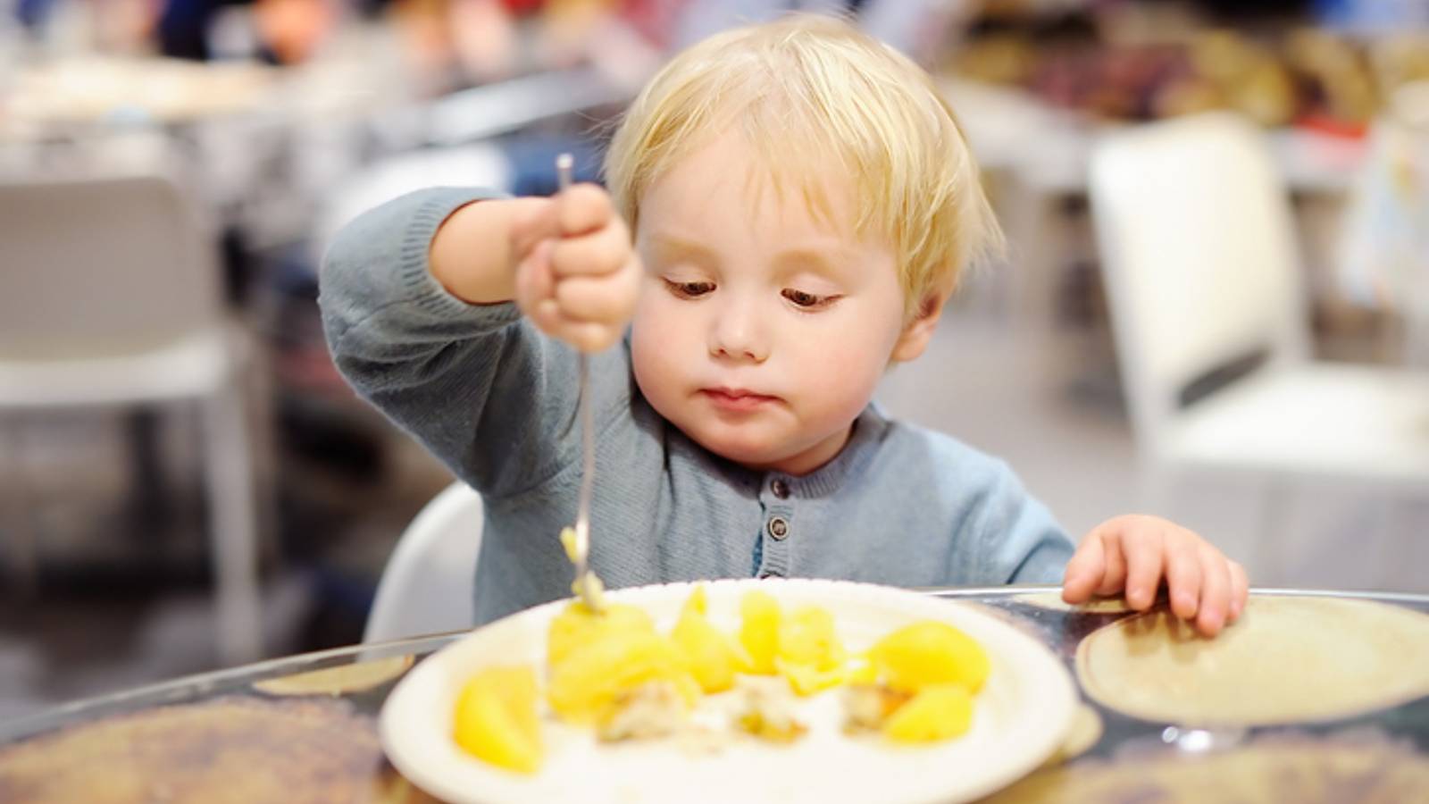 Family viewing a restaurant menu at an outdoor hotel cafe. 